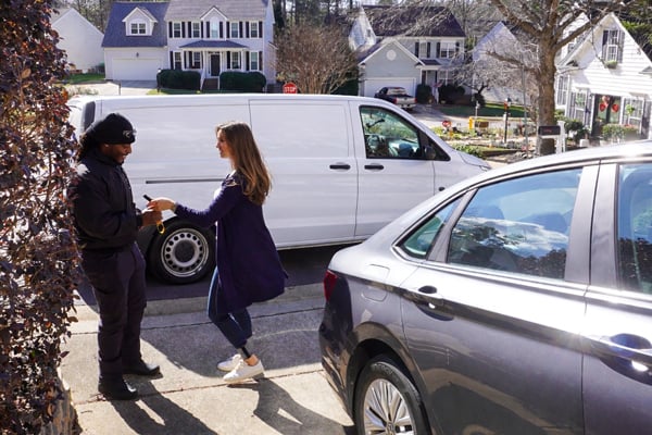 A mobile technician greeting a customer before beginning a mobile service on her vehicle.