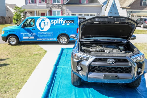 Spiffy oil van is in the background of a customer's Oil change service at home