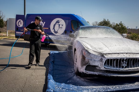 Spiffy technician at work location washing car on eco-friendly wash mat