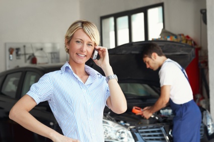 A multi tasking woman, conducting her work, while her car gets repaired at the auto shop