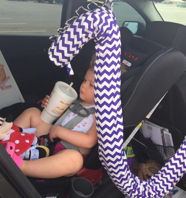 A toddler drinking a soda in a car seat
