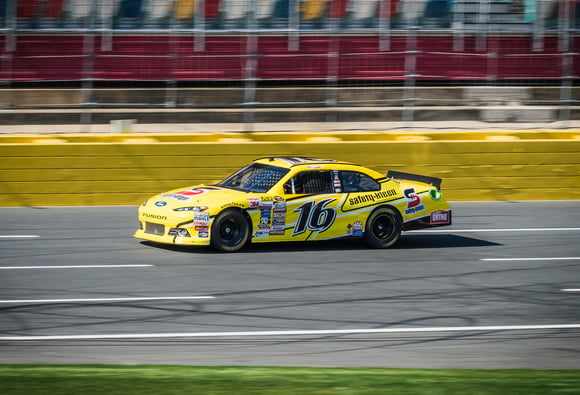 Charlotte Motor Speedway yellow car racing on track Charlotte Motor Speedway yellow car racing on track