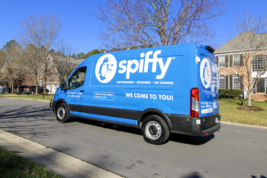 Branded Spiffy Van driving through a neighborhood